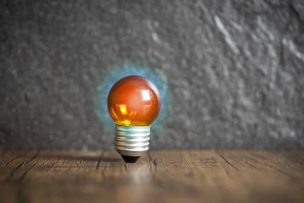 Ideenkonzept mit orangefarbener Glühbirne und blauem Licht auf Holzwitz — Stockfoto