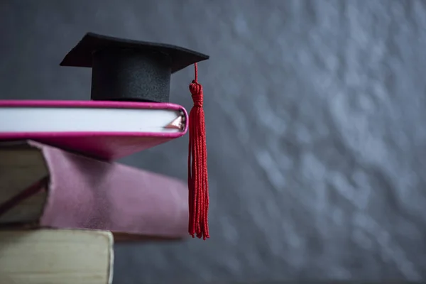 Concept d'éducation avec chapeau de graduation sur un livre avec backgr sombre — Photo