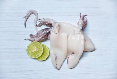 Taze kalamar masanın üst görünümünde / Çiğ kalamar ve limon kireç üzerinde whit