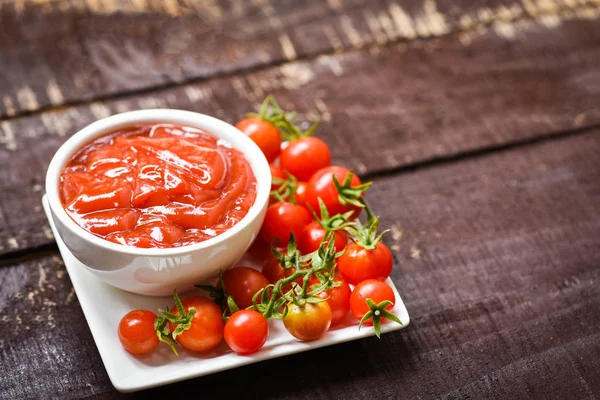 Ketchup en tasse et tomates fraîches sur assiette blanche / Fermer toma — Photo