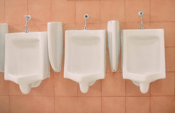 Fila de blocos sanitários urinários para o homem na parede de azulejos em trabalho público — Fotografia de Stock