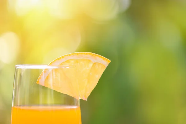 Jus d'orange avec morceau de fruit orange sur verre vert nature — Photo