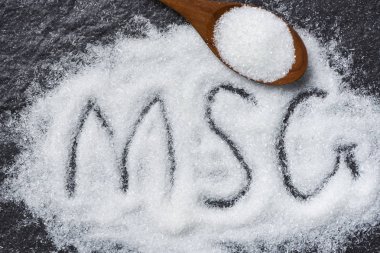Tahta kaşık ve koyu arka plan üzerinde monosodyum glutamat yığını
