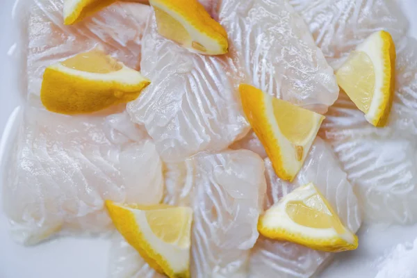 Świeże surowe ryby filet kawałek z cytryną na białym tle płyty — Zdjęcie stockowe