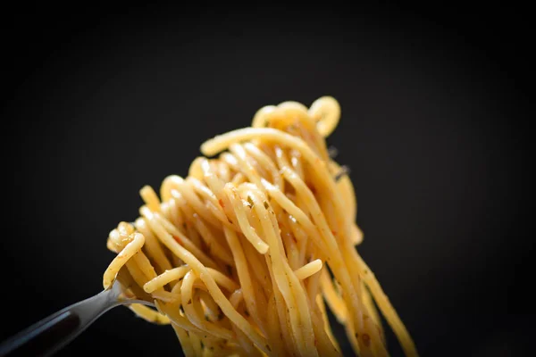 Widelec spaghetti na ciemnym czarnym tle-tradycyjne pyszne — Zdjęcie stockowe