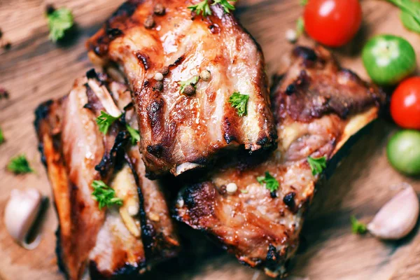 Bbq pork ribs grilled with tomatoes herbs and spices on wooden c — Stock Photo, Image