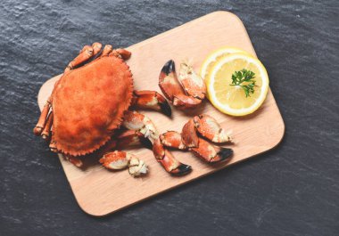 Pişmiş yengeçler siyah plaka se üzerinde limon ile ahşap tahta üzerinde haşlanmış
