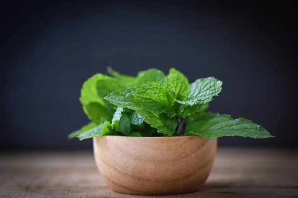 Peppermint leaf in a wood bowl - Fresh mint leaves on dark backg — Stock Photo, Image