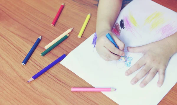 Chica pintura en hoja de papel con lápices de color en la t de madera —  Fotos de Stock