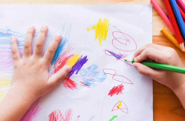 Fille peinture sur feuille de papier avec crayons de couleur sur le t en bois — Photo