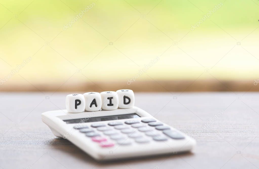 Paid words and calculator on table for time paid payment at offi