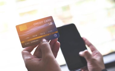 Kadın elleri kredi kartı tutarak ve online için akıllı telefon kullanarak 