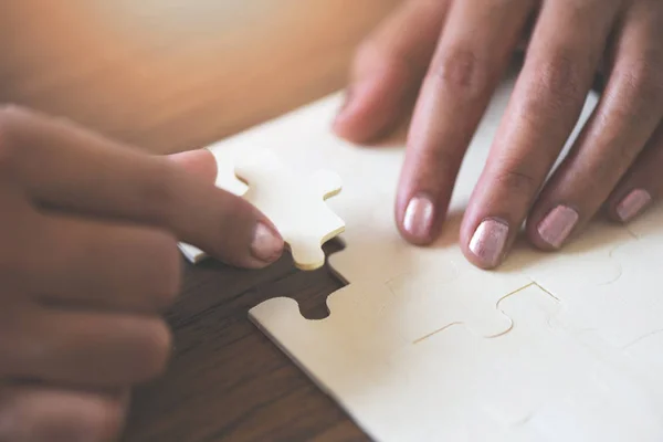 Puzzle mit Frauenhand verbindet Puzzleteil auf Holz — Stockfoto