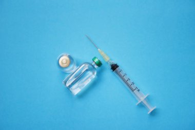 Mavi sırt üzerinde ilaç şişeleri cam ve şırınga enjeksiyon iğnesi