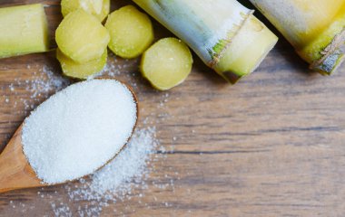 Tahta masada kaşık ve şeker kamışı üzerinde beyaz şeker 