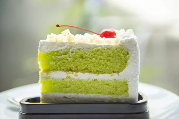 Fetta di torta verde con ciliegia e panna su palte bianca su t — Foto Stock