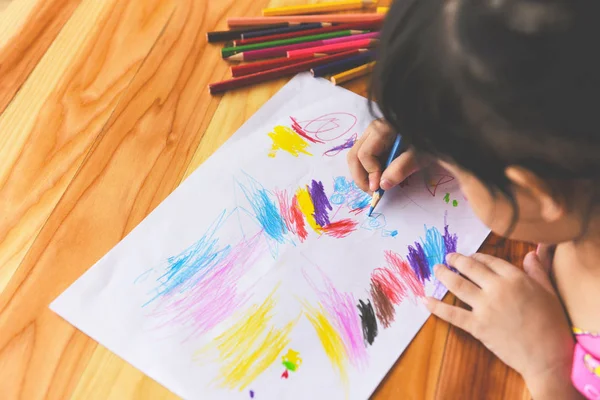 Chica pintura en hoja de papel con lápices de color en la t de madera —  Fotos de Stock