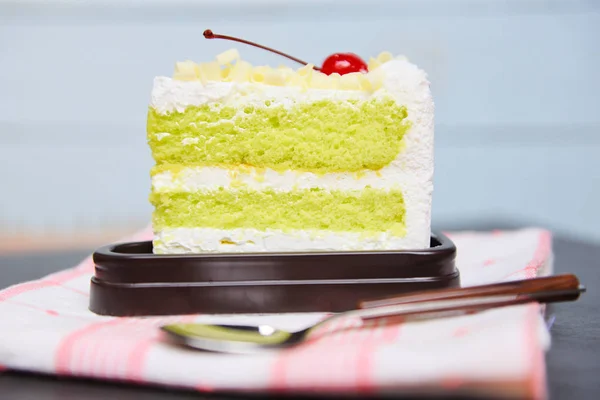 Fetta di torta verde con ciliegia e panna su palte bianca su t — Foto Stock