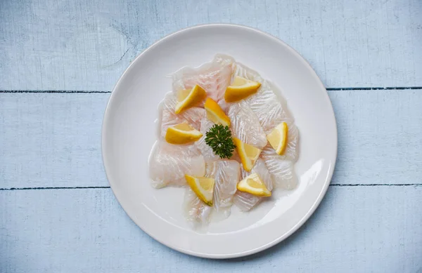 Филе сырой рыбы с лимоном на белой тарелке - Закрыть пангу — стоковое фото
