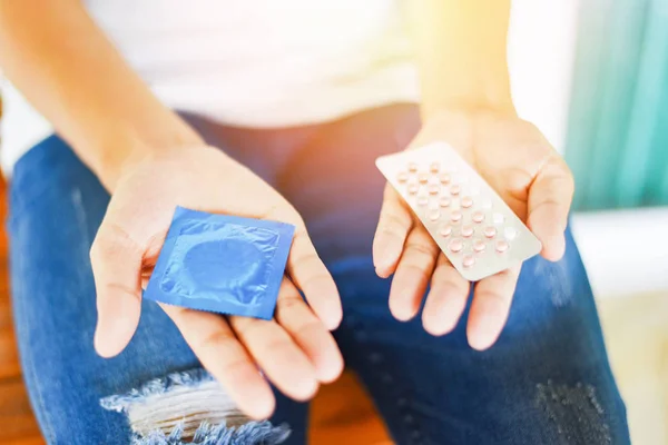 Mulher segurando pílulas de contracepção e preservativo na mão - Birth con — Fotografia de Stock