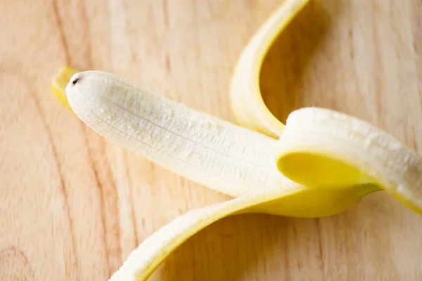 Buccia di banana - Primo piano di fresco maturo un frutto di banana sbucciato su wo — Foto Stock