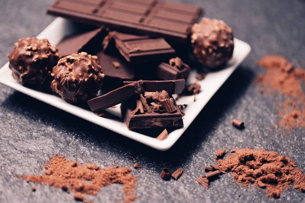 Čokoládová tyčinková a čokoládová koule na bílé desce na tmavém zádech — Stock fotografie