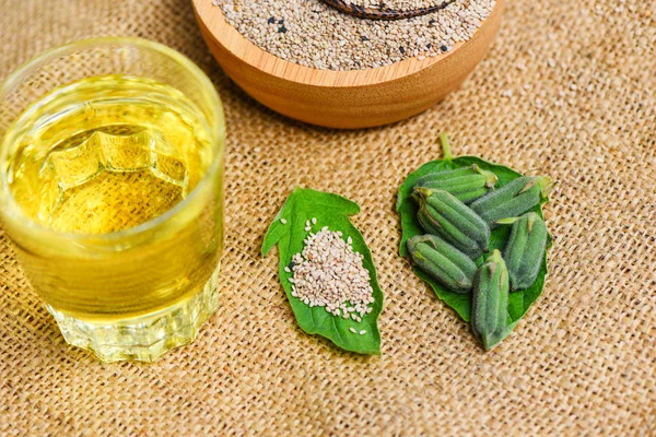 Sesame seeds in a wooden bowl and green leaf with sesame oil gla — Stock Photo, Image