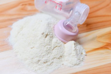 Ahşap masa üzerinde süt tozu ve bebek şişesi süt 