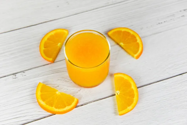 Jus d'orange dans le verre et tranche d'orange fraîche sur bois — Photo