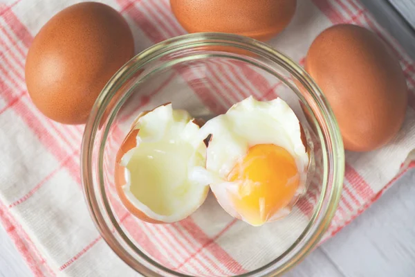 Gekookt ei op glazen kom en verse eieren op de achtergrond van de tafel — Stockfoto