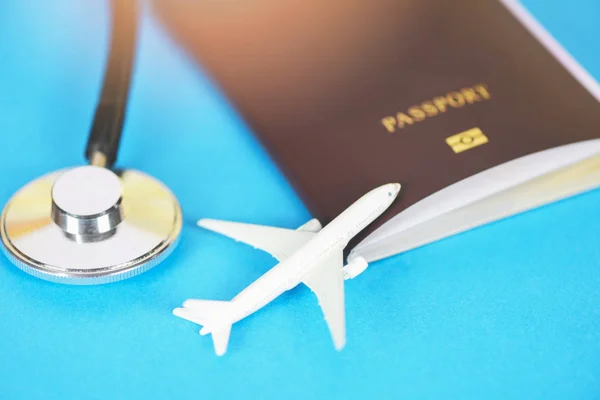 Mavi backgroun pasaport ve stetoskop ile seyahat sigortası — Stok fotoğraf