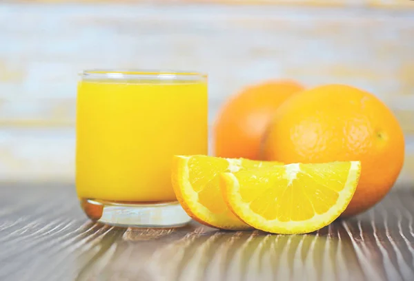 Jus d'orange dans le verre et tranche d'orange fraîche sur bois — Photo