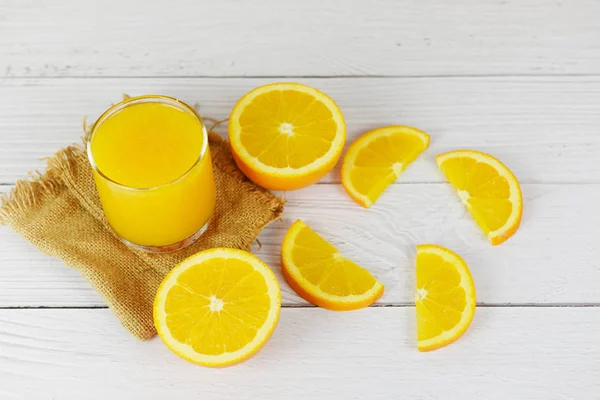 Sok pomarańczowy w szklance i świeży pomarańczowy kawałek owoców na drewnianych — Zdjęcie stockowe