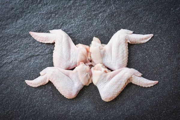Rohe Hühnerflügel auf schwarzem Teller Draufsicht - rohes rohes Huhn — Stockfoto