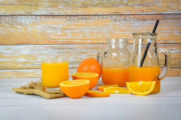 Sok pomarańczowy w szklanym słoiku i świeży pomarańczowy kawałek owoców na wo — Zdjęcie stockowe