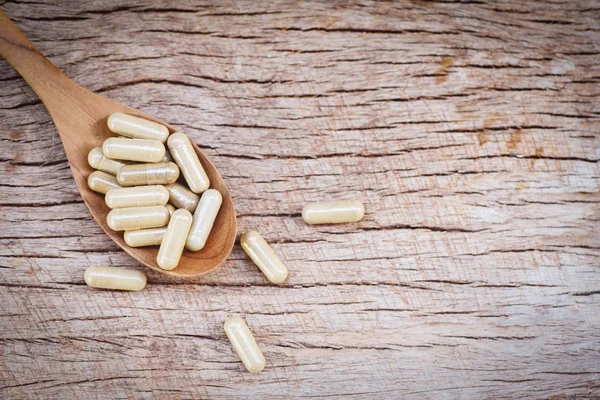 Medicamentos a base de hierbas / Cápsulas de hierbas naturales en cuchara de madera y rus — Foto de Stock