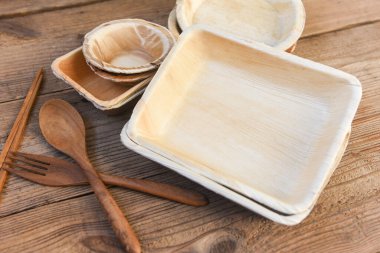 Doğal çevre dostu yiyecek ambalajı bulaşık kabı ve ahşap çatal kaşığı ile tek kullanımlık mutfak eşyaları, palmiye yaprağı veya betel cevizi ile çevrenin sıfır atığı konsepti.