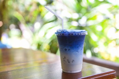 Kelebek bezelye suyu ya da mavi bezelye çiçeği. Ahşap zemin üzerinde süt içmek için bitkisel çay. 