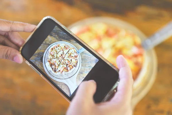 Food photography woman hands make photo Pizza with smartphone / taking photo food for post and share on social networks with camera smart phone in restaurant