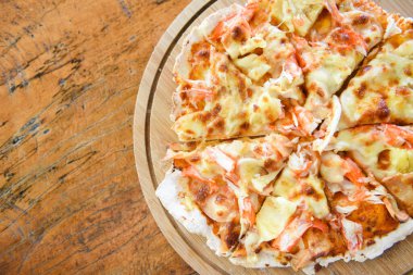 Tahta tepside pizza dilimi ve ahşap bir masada servis edilen ev yapımı hamur pizzası İtalyan yemeği.