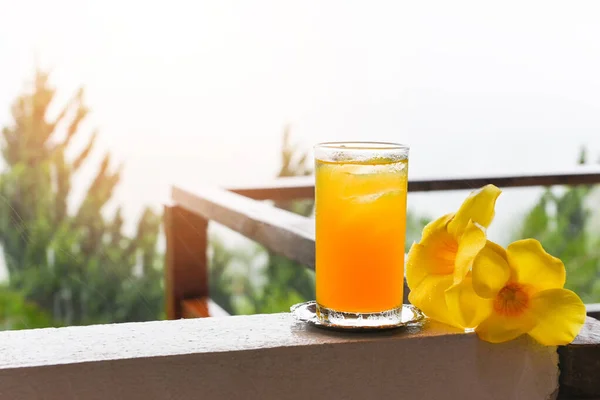 Szklanka Soku Pomarańczowego Żółtym Kwiatem Balkonie Kroplami Deszczu Rano — Zdjęcie stockowe