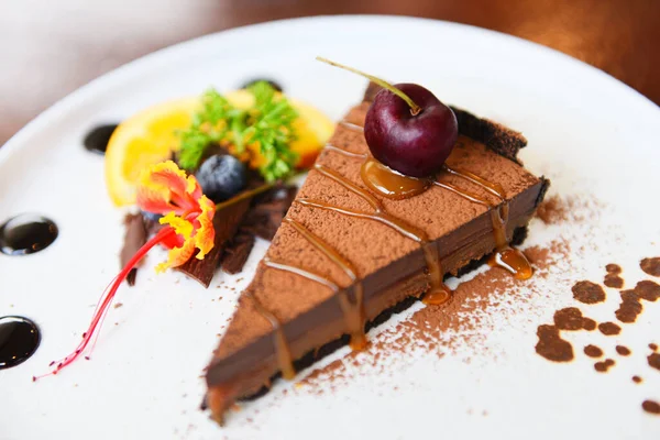 Chocolate cake caramel with cherry and fruit on white plate / Close up cake slice