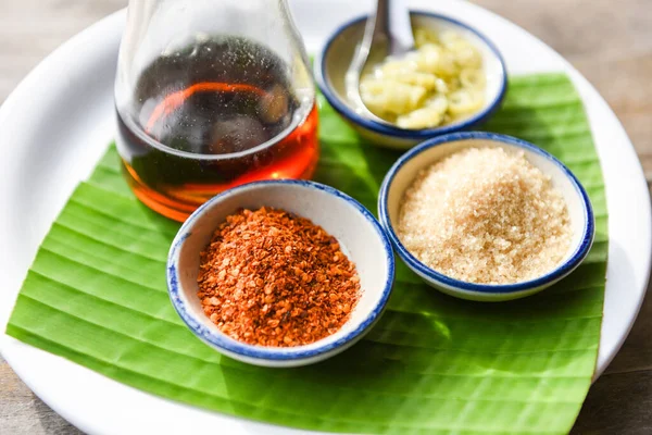 seasoning food with chili powder , sugar , fish sauce and vinegar on banana leaf