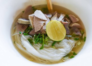 Lezzetli erişte kasesi / vermicelli şehriye çorbası baharatlı domuz yahnisi sebze ve limonlu kase geleneksel Tayland ve Çin usulü Asya yemeği, domuz sakatatı, ciğer domuz bağırsağı.