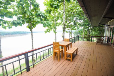 Tahta masa ve sandalyeler balkonda ve doğa yeşil ağaç ormanı / balkon manzaralı nehir, teras evi