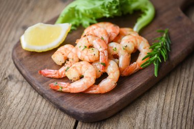 Salata karidesi ızgara lezzetli baharatlar ahşap kesim tahtası arka planda iştah açıcı pişmiş karides fırınlanmış karides, biberiye limonlu deniz ürünleri ve marul.