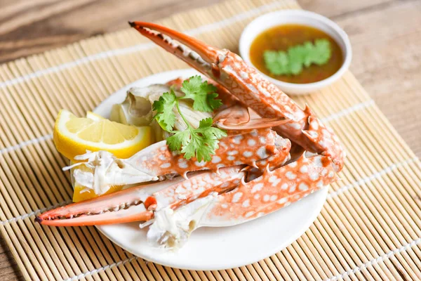 Boiled crab food on white plate and seafood sauce on the table / crab claws shellfish