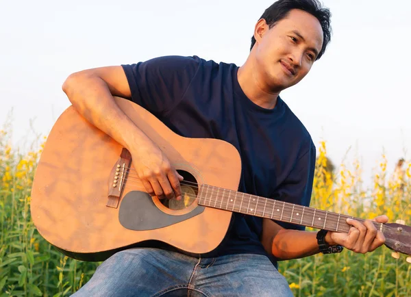 Men playing guitar in Beautiful Sunhemp flower in garden