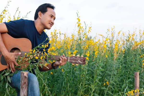 Mężczyzn Gra Gitarze Sunhemp Piękny Kwiat Ogrodzie — Zdjęcie stockowe