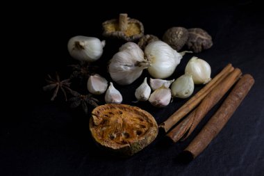Sarımsak ve kuru bael meyve çayı ve Mantar, tarçın, Yıldız anason siyah arka plan izole